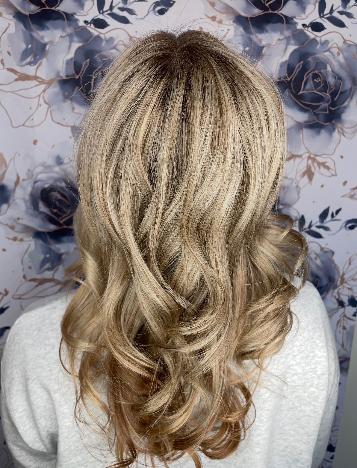 Back view of long dimensional blonde hair styled in soft curls.