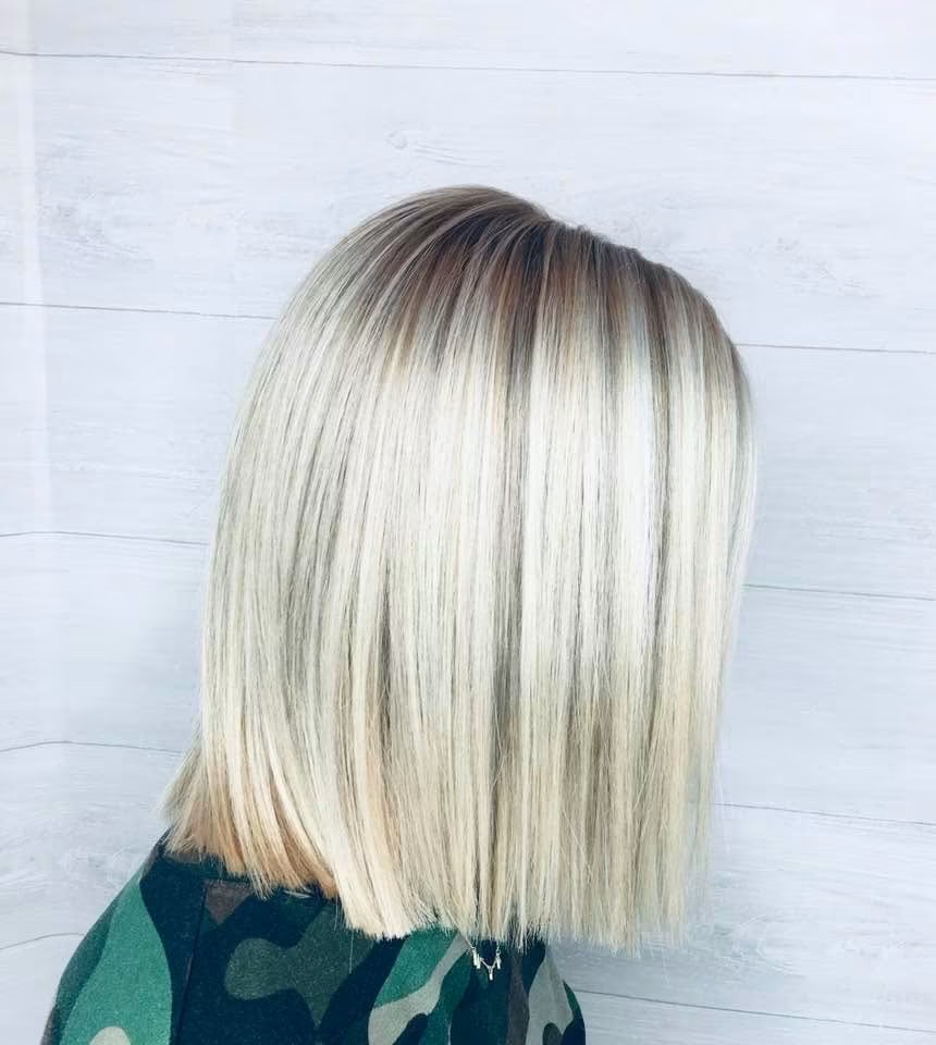 Side-back view of a sleek, blunt blonde bob with a softly shadowed root.