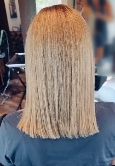 Back view of a sleek, shoulder-length blonde lob cut to one blunt line.