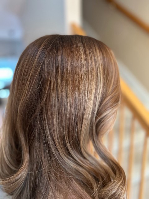 Back view of the same brunette hair with soft bronde ribbons and waved ends.