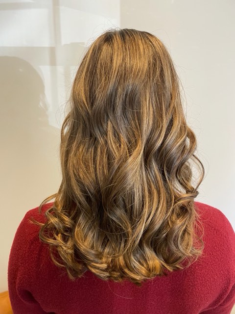Caramel dimension: shoulder-length brunette hair with caramel pieces in soft curls, seen from behind.