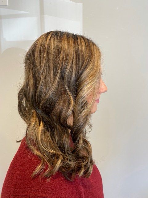 Side view of the same brunette hair with caramel dimension through the curls.