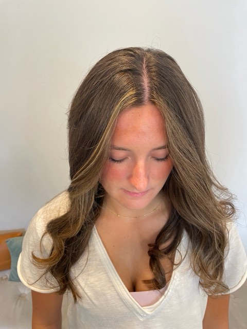 Front view of the same brunette with lighter pieces framing the face from a center part.