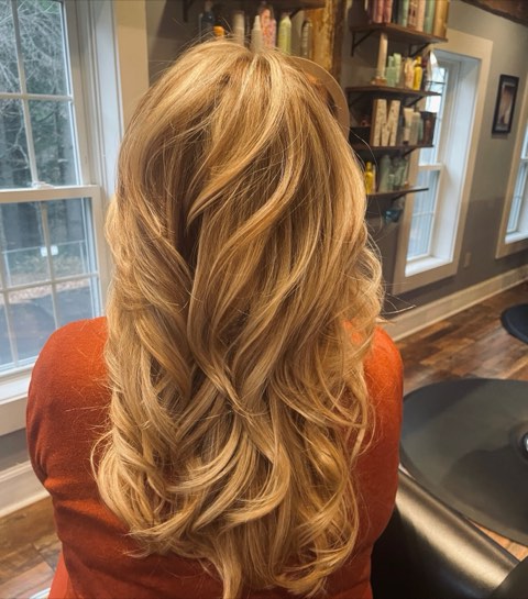Back view of long, layered golden-blonde hair with a full, bouncy blowout.