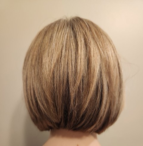 Back view of a honey-blonde bob with lighter dimensional pieces and a smooth, rounded shape.