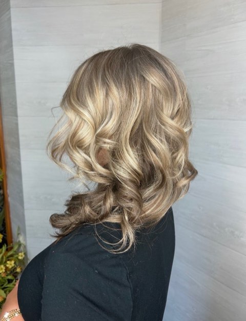 Back view of the same brunette hair showing blended highlights and loose curls.